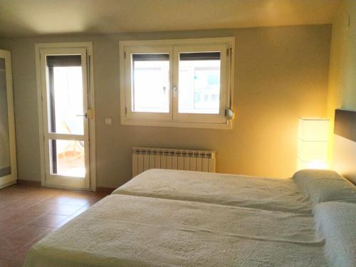 a bedroom with a bed and two windows at Apartamento EntreRíos in Barbastro