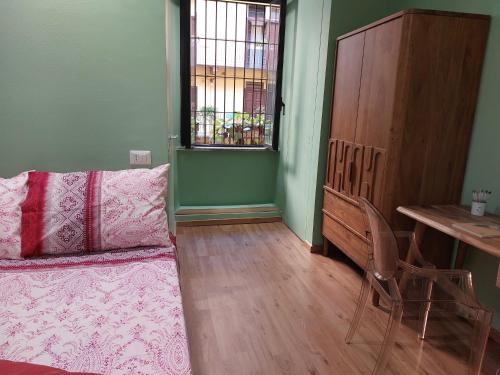 um quarto com uma cama, uma mesa e uma janela em 2 Via Fabio Mangone em Milão