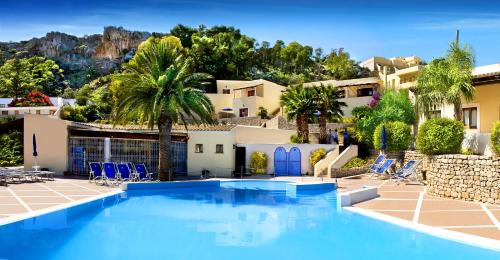 uma piscina com cadeiras azuis e uma casa em Villaggio Cala Mancina em San Vito lo Capo