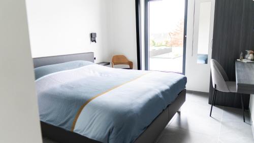 a bedroom with a bed and a desk and a window at B&B Koor91 in Hasselt