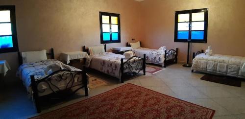 una habitación con cuatro camas y una habitación con ventanas en maison familiale chez Salwa, en Ouarzazate
