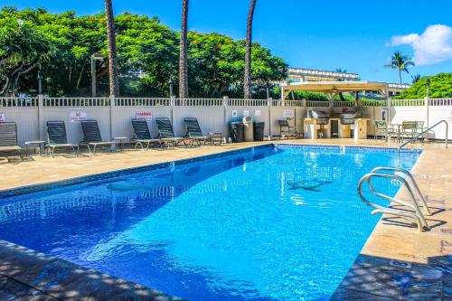 a large swimming pool with chairs and a fence at Kihei Akahi in Wailea