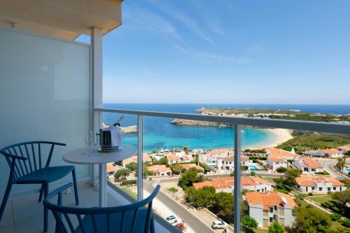 a balcony with two chairs and a view of the ocean at Palladium Hotel Menorca in Arenal d'en Castell