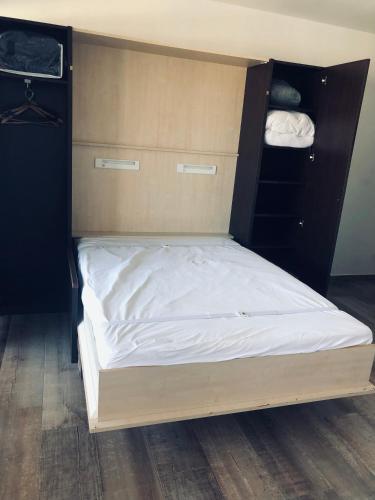 un lit avec des draps blancs et une tête de lit en bois dans l'établissement Studio climatisé avec piscine, vue mer, à Sainte-Maxime