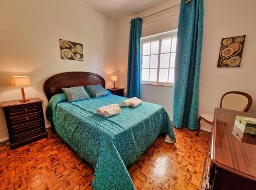a bedroom with a bed with a green comforter and a window at Tavira City Center 3Br in Tavira