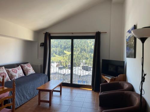 a living room with a couch and a sliding glass door at Apartaments Casa Vella Popaire in Soldeu
