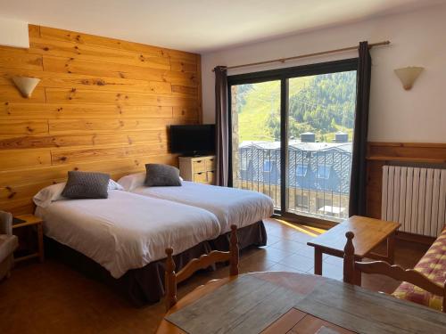 a bedroom with two beds and a large window at Apartaments Casa Vella Popaire in Soldeu
