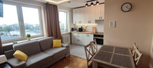een woonkamer met een bank en een tafel en een keuken bij Labo Apartment Platynowa in Warschau