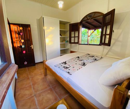 Cette chambre comprend un grand lit et une fenêtre. dans l'établissement Magnifique Lodge en bois avec piscine et jardin de 800 m2, au Lamentin