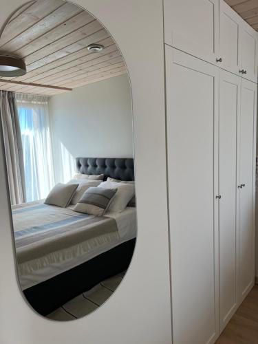 Schlafzimmer mit einem Bett und einem Spiegel in der Unterkunft Apartamentai “VASARA” Malūno vilose in Palanga
