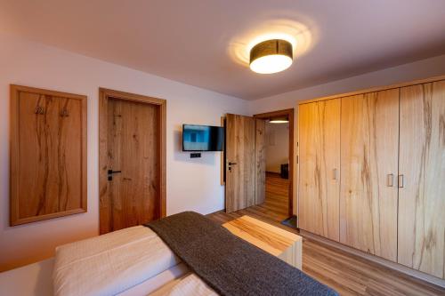 a bedroom with a bed with wooden cabinets and a tv at Rustika - Appartements & Spa in Ehrwald