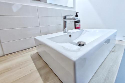 Baño blanco con lavabo y espejo en L'Escale cocooning T3 Centre ville, en Bagnères-de-Bigorre