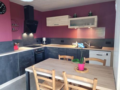 een keuken met een tafel en stoelen en een paarse muur bij Gîte à la ferme du Lomont 