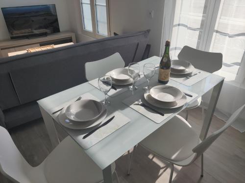 - une table blanche avec des verres et une bouteille de vin dans l'établissement Appartement T3 PLUME Hyper centre d'ERNÉE, à Ernée