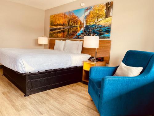 a hotel room with a bed and a blue chair at Days Inn by Wyndham Ardmore in Ardmore