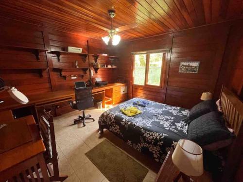 een slaapkamer met een bed en een bureau met een computer bij Casa de Campo em Penedo - RJ in Itatiaia