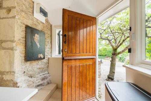a wooden door in a kitchen with a window at Architect Designed Cosy Cotswold Stone Cottage in Quenington