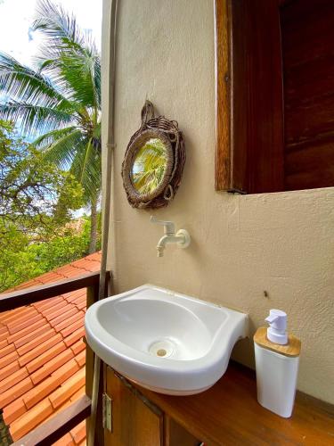 a white sink in a bathroom with a palm tree at Pousada Velho Bateau in Atins