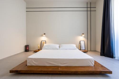 a bedroom with a large white bed with a wooden platform at labotanica_casalounge in Cesenatico