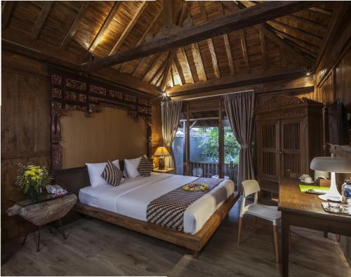 a bedroom with a bed and a desk in a room at Rumah Batu Boutique Hotel in Solo