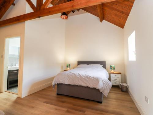 a bedroom with white walls and a bed and a wooden ceiling at Wren cottage in Sandbach