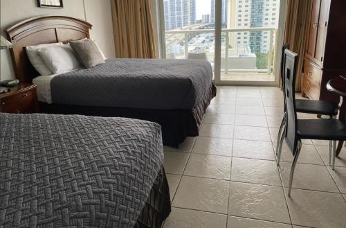 a hotel room with two beds and a balcony at Ramada Marco Polo Beach in Miami Beach