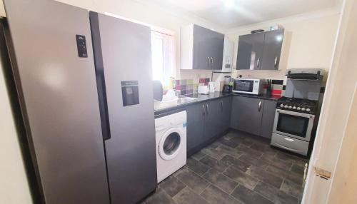 a kitchen with a refrigerator and a washer and dryer at Comfy Apartment Near Shops & Station in Slough