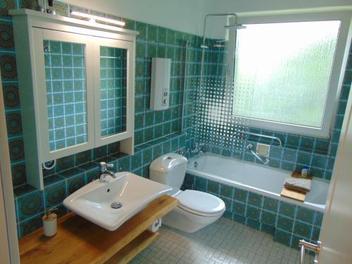 La salle de bains est pourvue de carrelage bleu, d'un lavabo et de toilettes. dans l'établissement Harz Reloaded Thomsen, à Hahnenklee