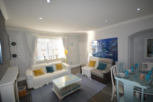 a living room with couches and a table with a table at Sandridge in Newbiggin-by-the-Sea