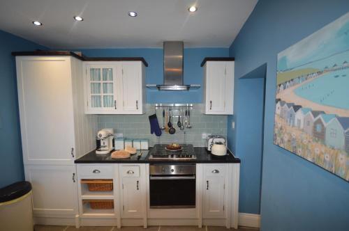 a kitchen with white cabinets and a blue wall at Sandridge in Newbiggin-by-the-Sea