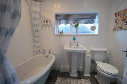 a bathroom with a tub and a toilet and a sink at Sandridge in Newbiggin-by-the-Sea