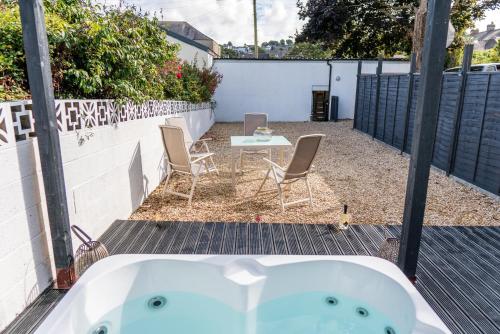 a bath tub in a backyard with a table and chairs at Parke -HotTub- Apartment in Pembroke Dock