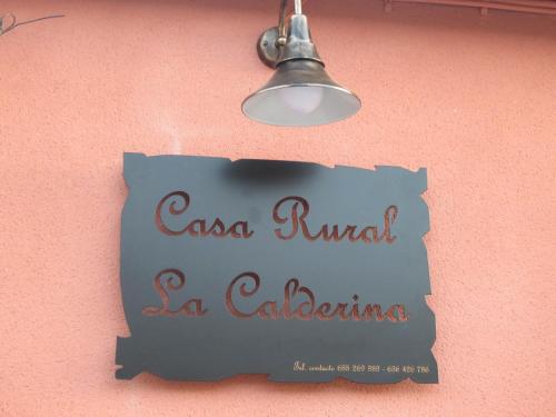 a sign on a pink wall with a light at Casa Rural La Calderina in Urda