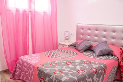 een slaapkamer met een groot bed en roze gordijnen bij El Rincón de Soraya in Sanlúcar de Barrameda