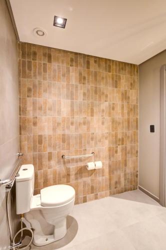 a bathroom with a toilet and a tiled wall at Slaviero Ponta Grossa in Ponta Grossa