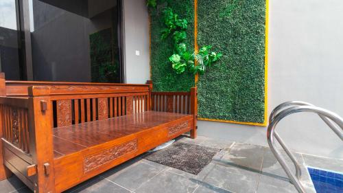 un banc en bois assis à côté d'un mur vert dans l'établissement Villa Private Pool Syariah Musim Liburan, à Batu