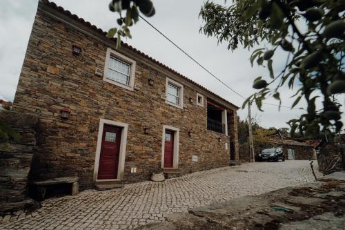 a brick building with red doors on a street at Forno House in Pereiros