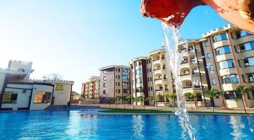 a fountain in the middle of a swimming pool with buildings at Sunset Paradise Holidays Homes in Shanzu