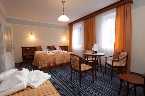 a hotel room with a bed and a table and chairs at Spa & Wellness Hotel Harmonie in Mariánské Lázně