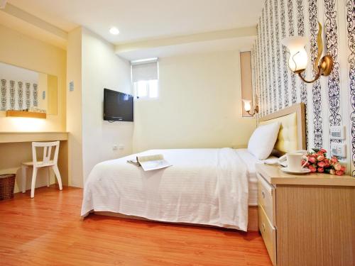 a hotel room with a white bed and a table at Green Park Commercial Hotel in Tainan