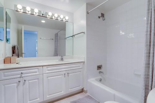 ein weißes Badezimmer mit einer Badewanne, einem Waschbecken und einem Spiegel in der Unterkunft Cozy 2 BR Condo At Arlington With Gym in Arlington