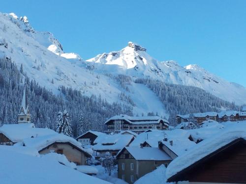a village covered in snow with a mountain in the background at Chalet Karin in Arabba