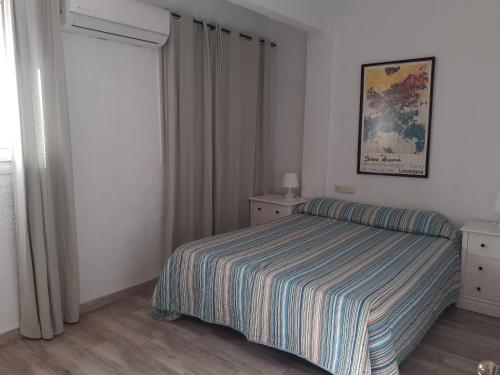 トレモリノスにあるApartamento Torremolinosのベッドルーム1室(ストライプ毛布付きのベッド1台付)