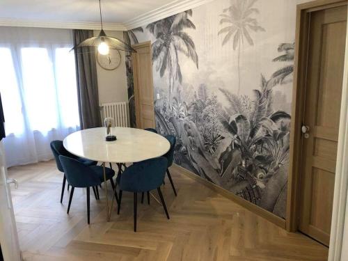 uma mesa e cadeiras num quarto com um mural de palma em Appartement Chez Bernadette à 50m de la plage em Saint-Cast-le-Guildo