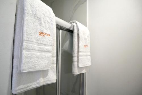 a bathroom with white towels hanging on a shower door at Amadora Boutique Hostel in Amadora