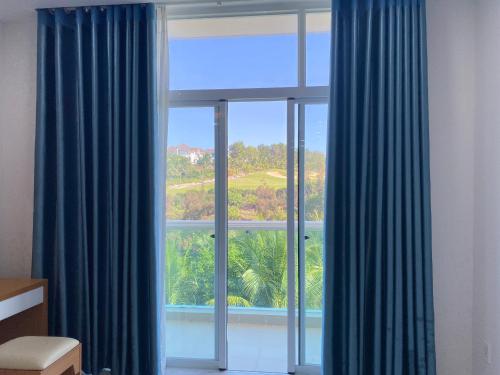 a room with a large window with blue curtains at Hotel,Căn Hộ Mũi Né Sea link in Phan Thiet