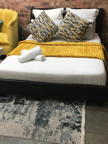 a bed with a yellow blanket and pillows on it at Maboneng Craftsmanship place in Johannesburg