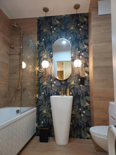 a bathroom with a tub and a sink and a mirror at M2 Bemowo apartament in Warszawa