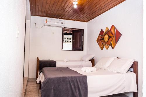 a room with two beds and a mirror on the wall at Pousada Bon Vivant in Porto De Galinhas