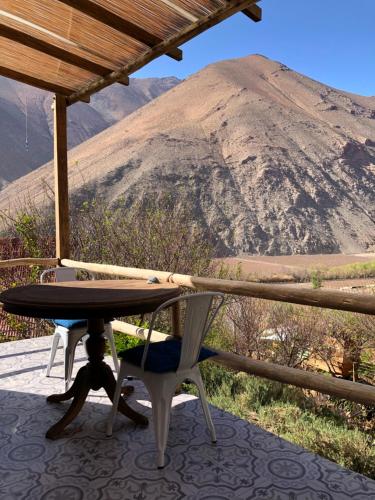 uma mesa e cadeiras num alpendre com uma montanha em Cabañas Elquimista em Pisco Elqui